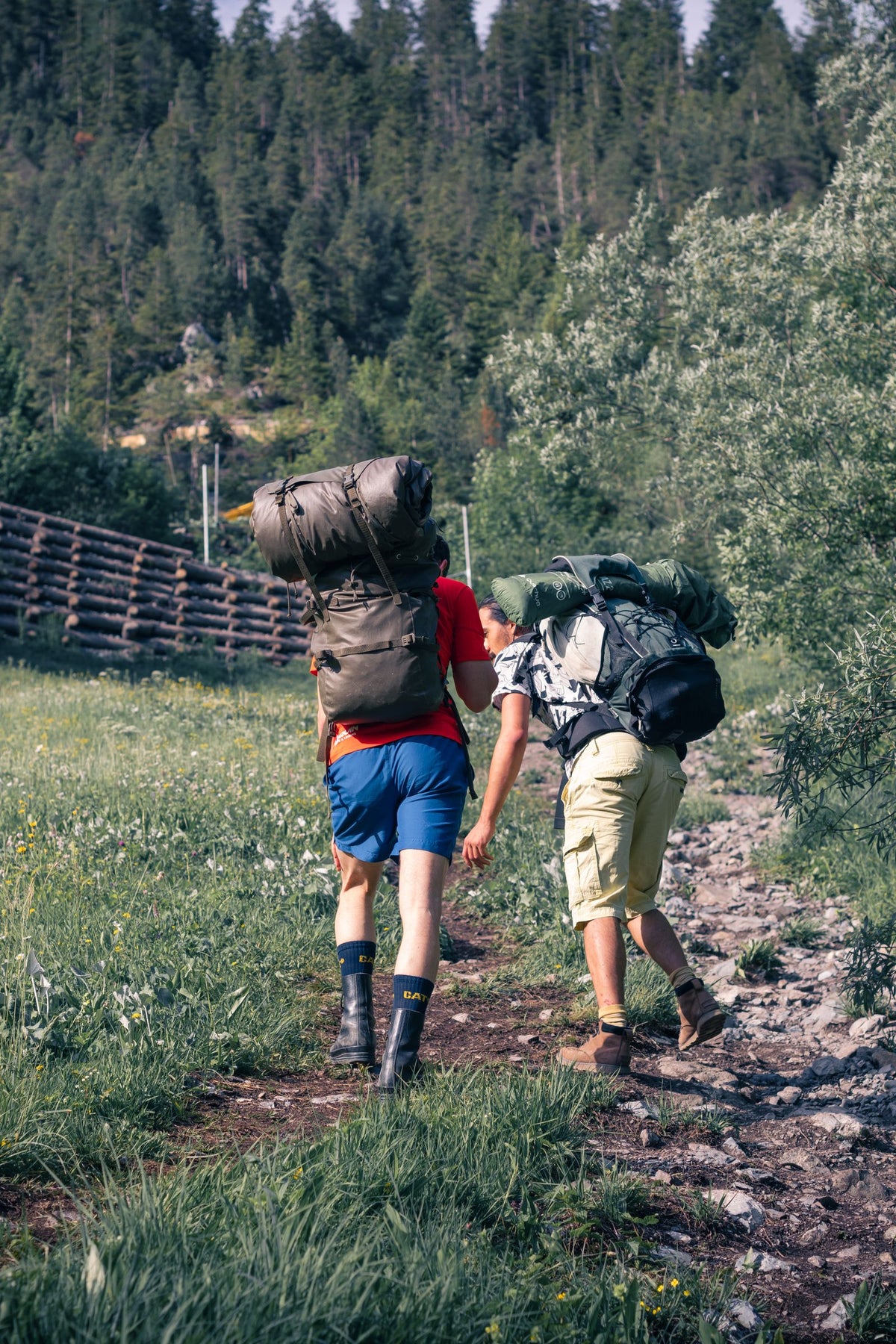Two hikers carrying backpacks on a forest trail