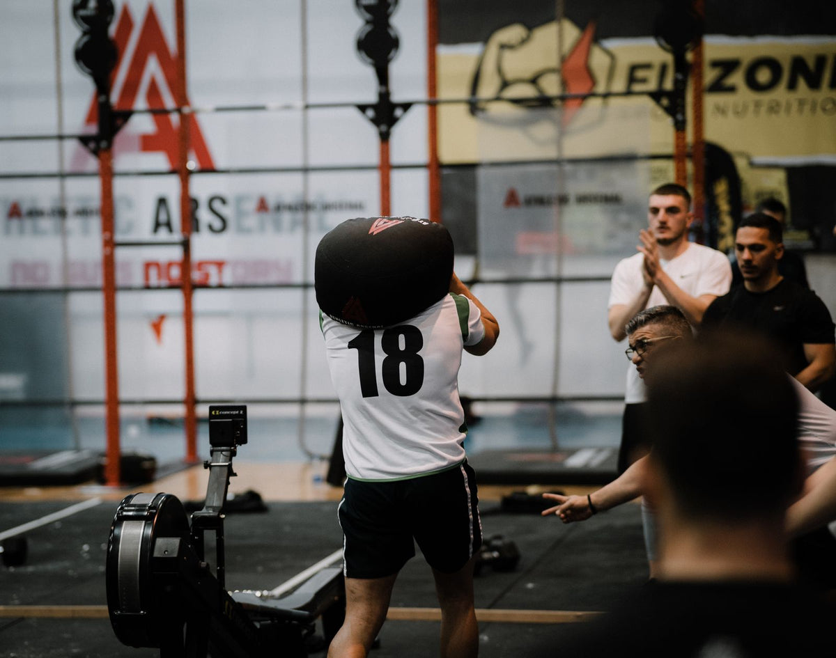 Athlete holding a training sandbag during an indoor fitness event