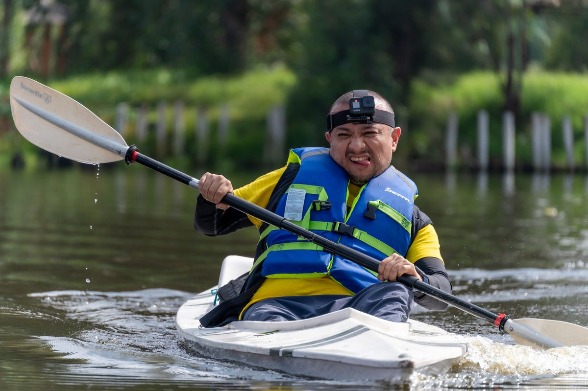 Man wearing a buoyancy aid paddling a kayak on a river