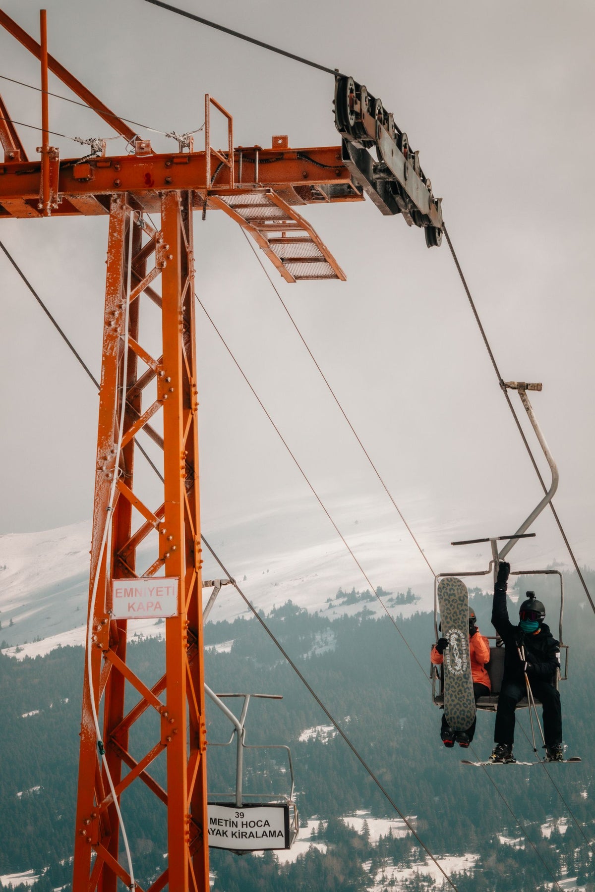 Snowboarders riding a ski lift over a snowy mountain
