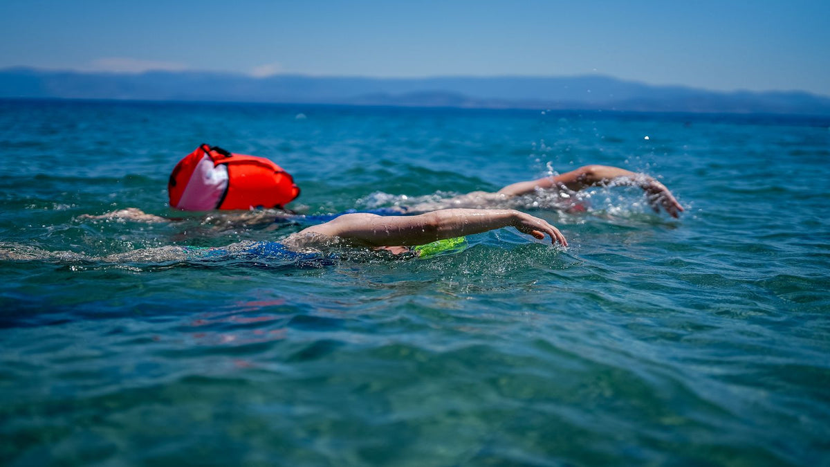 Two swimmers wearing caps in open blue water