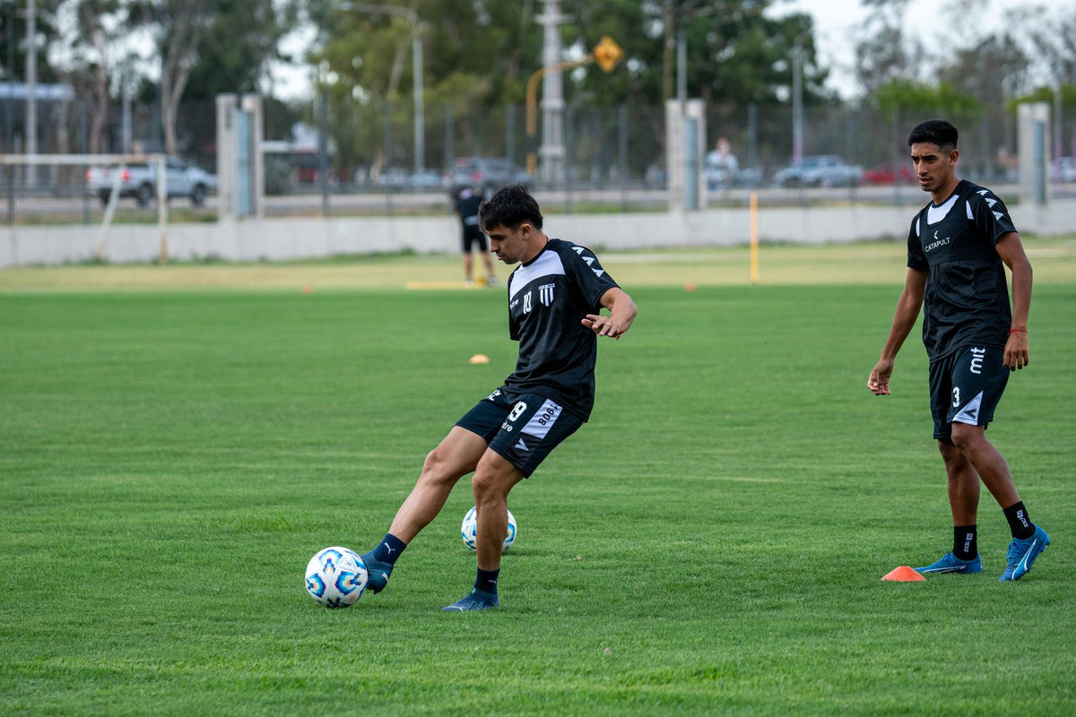 Two soccer players practising on a grass field