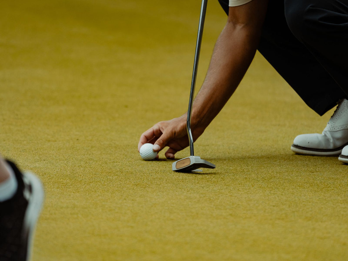 Golfer placing a ball on the putting green