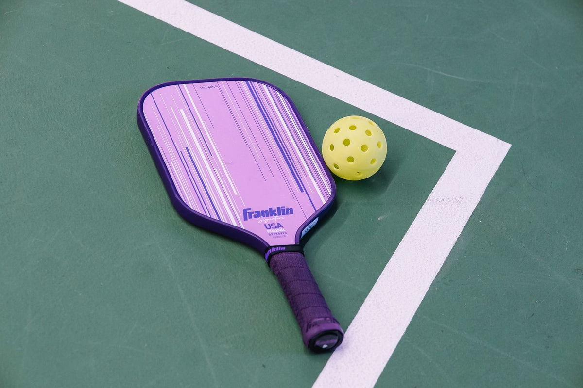 Pickleball paddle and ball on a green court