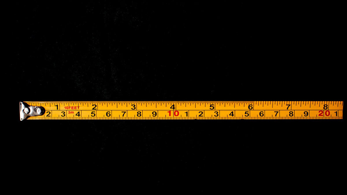 Yellow measuring tape laid out against a dark background