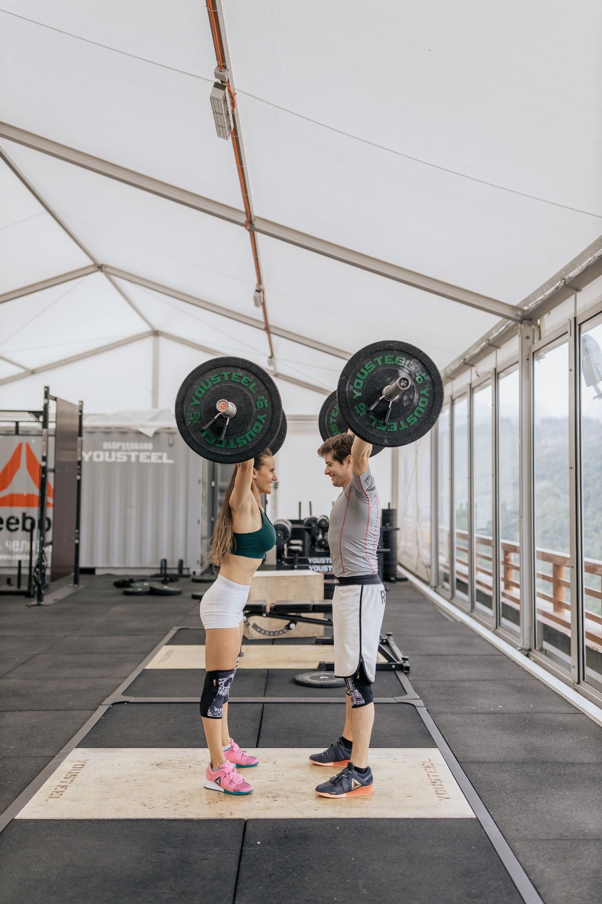 Two adults lifting barbells in an indoor gym