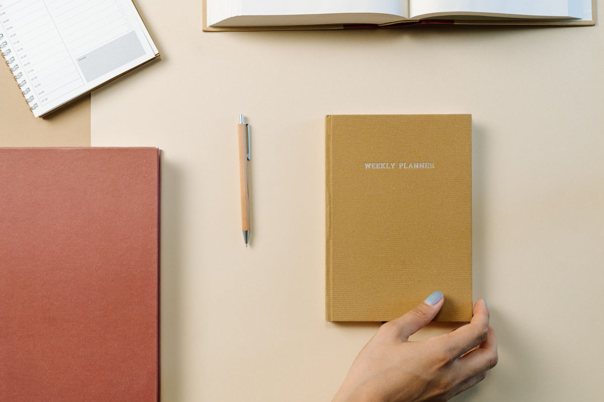 Open weekly planner, notebook and pen on a desk