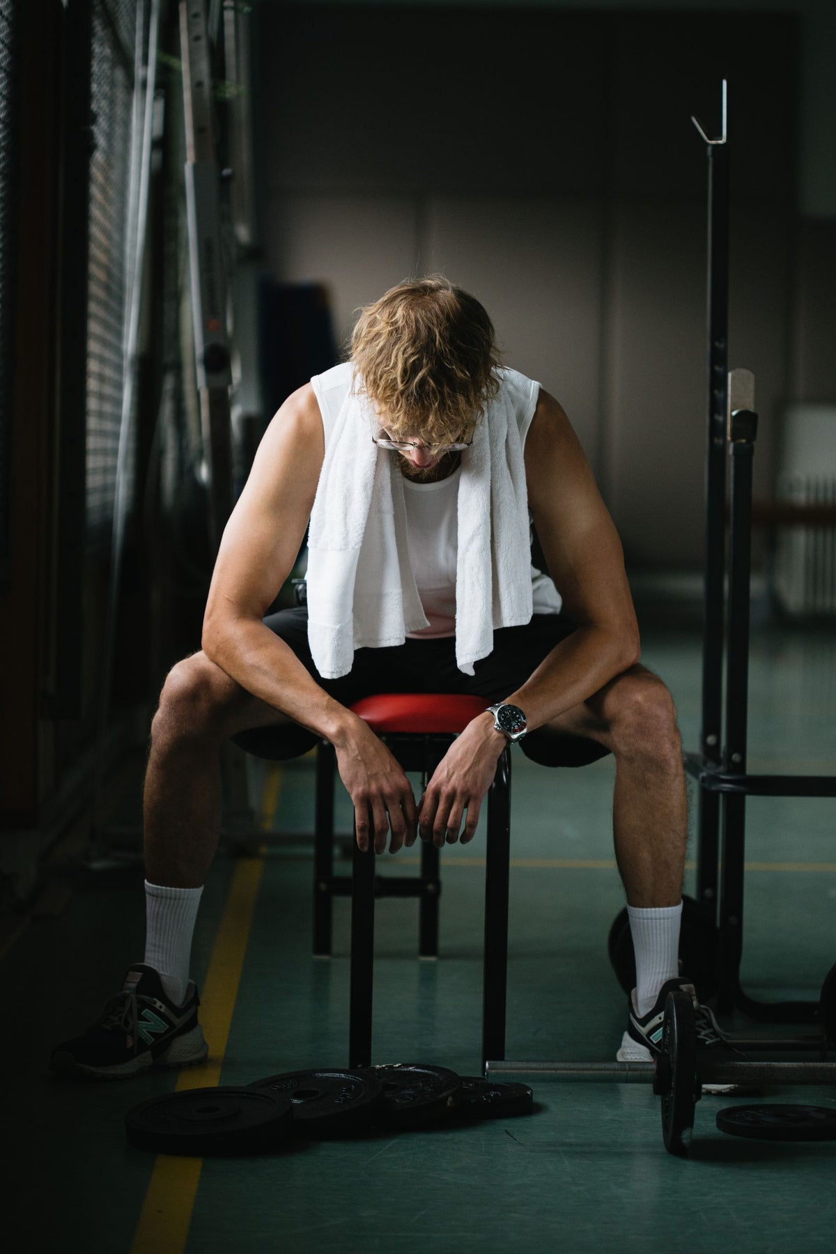 Man in sportswear sitting on a gym bench with a towel