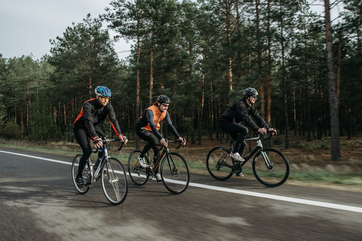 Cyclists riding together on a road beside trees