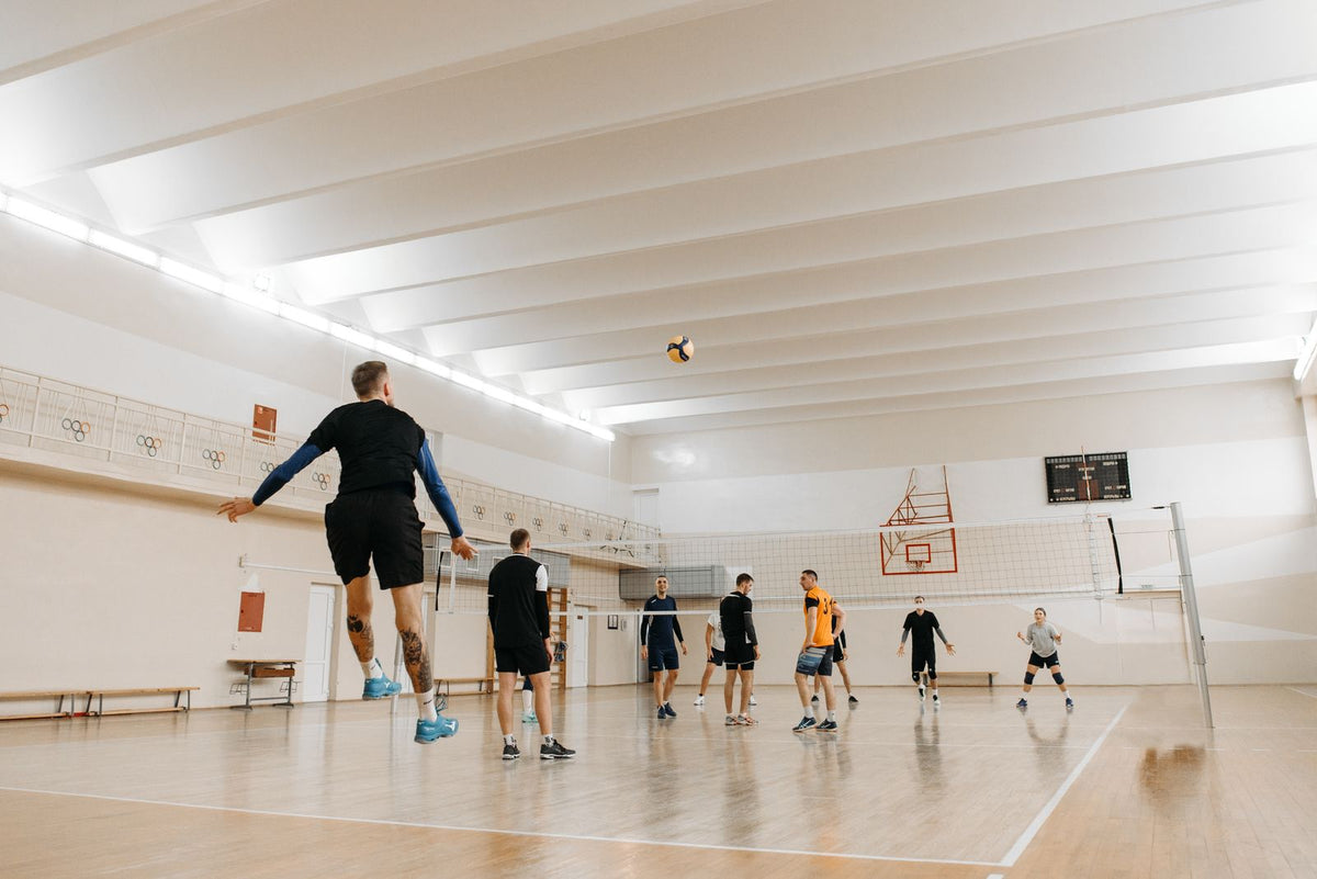 Volleyball players jumping at the net during an indoor game