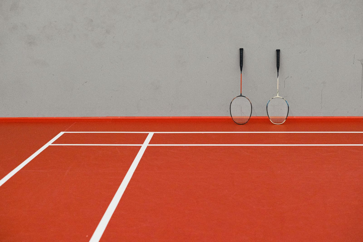 Badminton rackets beside a court wall