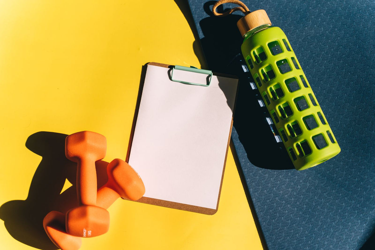 Phone, dumbbells and water bottle arranged on an exercise mat