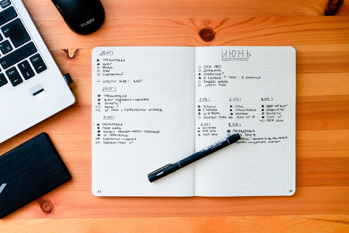 Open notebook and pen beside a laptop on a desk